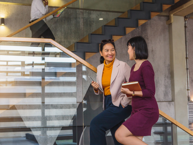Female employees talking while walking up stairs